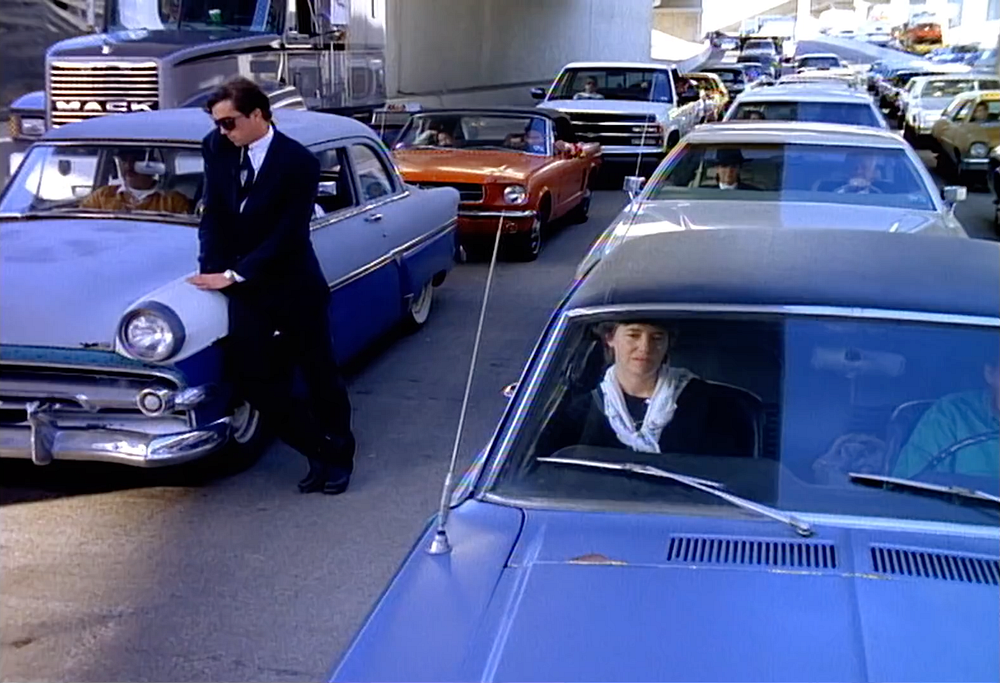 Cars standing in traffic. one man standing outside, leaning on a car