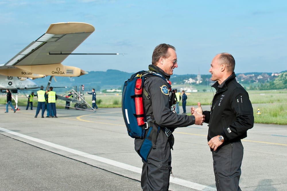 André Borschberg standing beside the Solar Impulse aircraft, symbolizing the fusion of human determination and solar-powered innovation