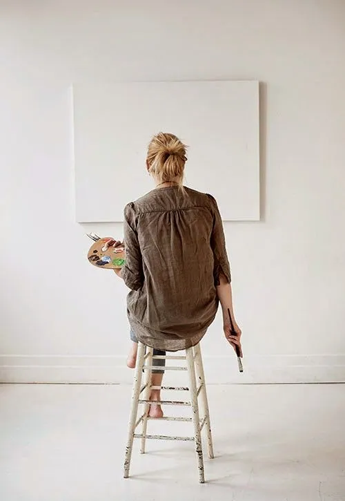 A person painting on a canvas attached to the wall