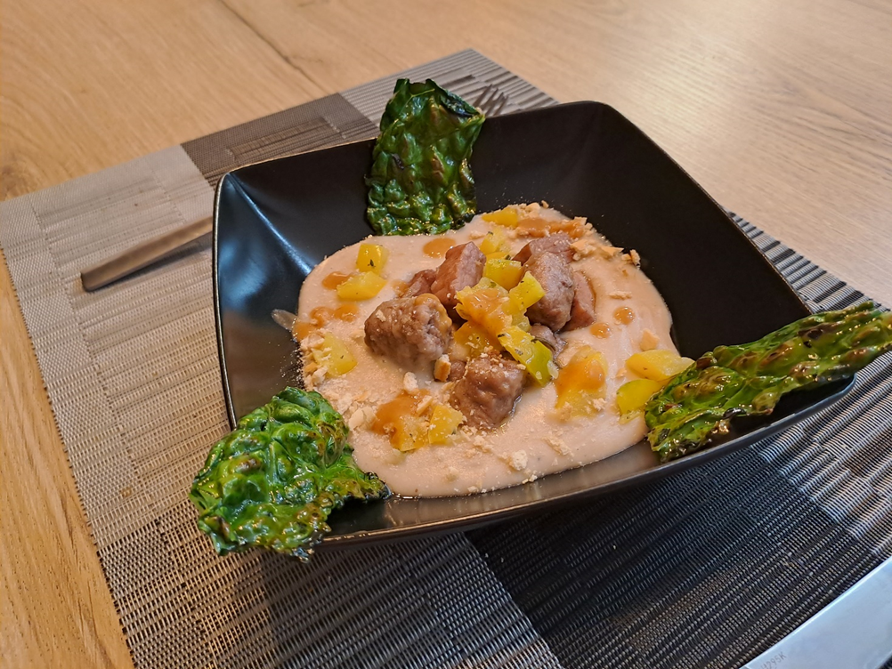 Stufato di carne su crema di fagioli cannellini, con dadolata di peperone e chips di cavolo nero