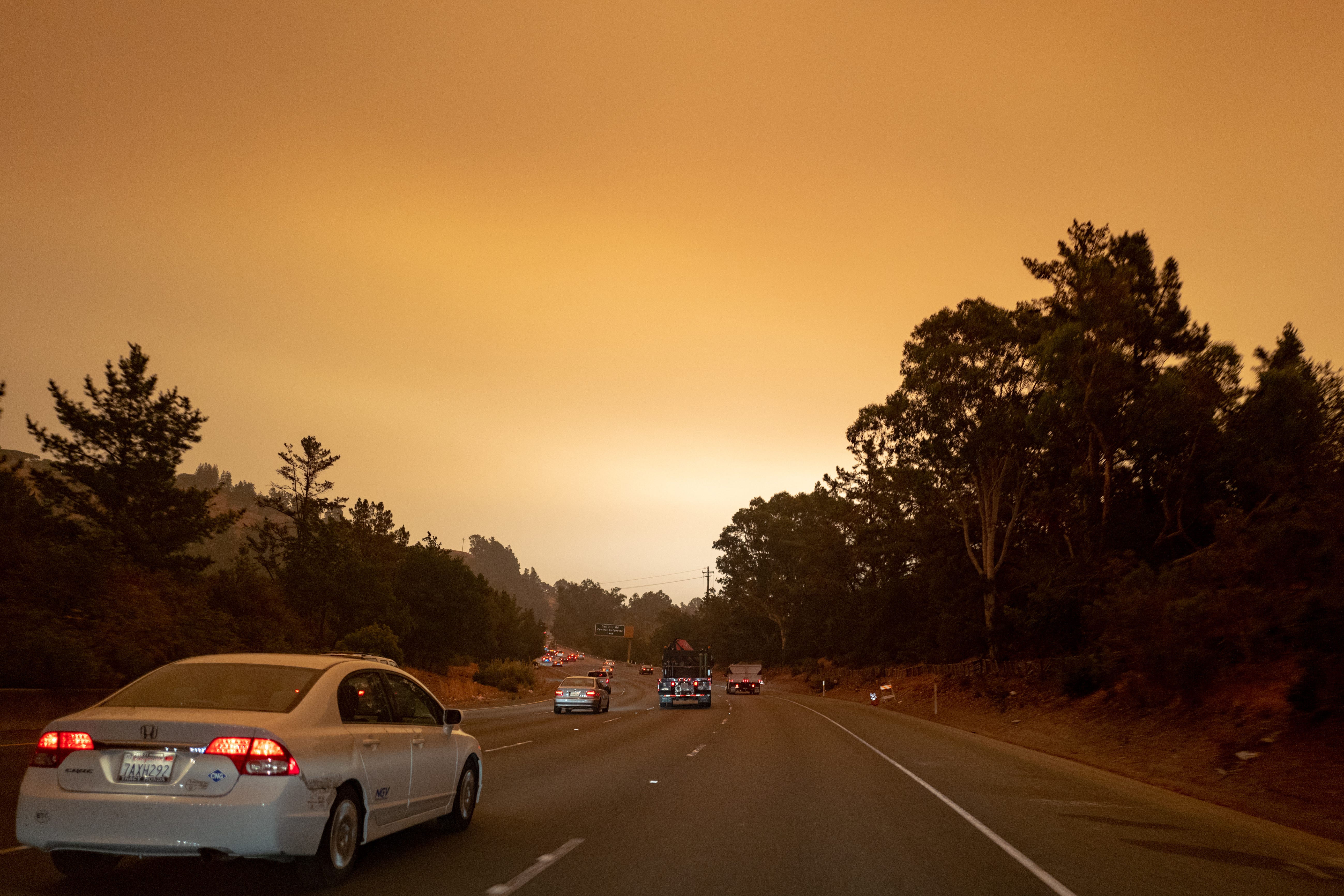 A highway with cars on it, under a smoky orange sky.