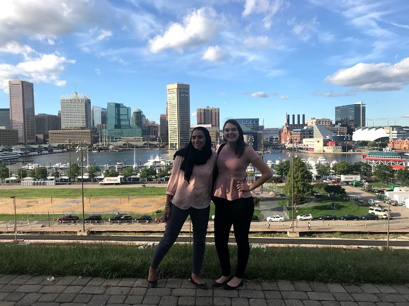 Two women posing in front of a city.
