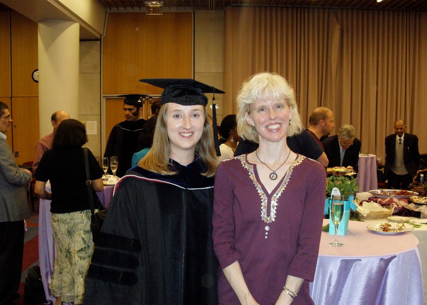 Photo of Mary Ellen Wiltrout wearing a graduation cap and gown next to Tania Baker in a banquet hall.