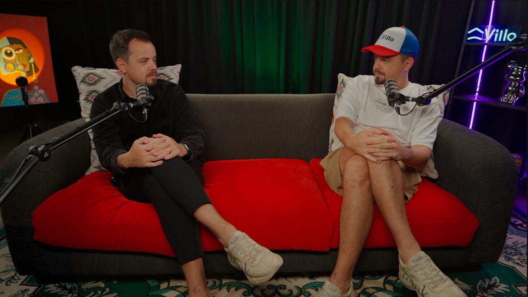 2 men seating on a red sofa
