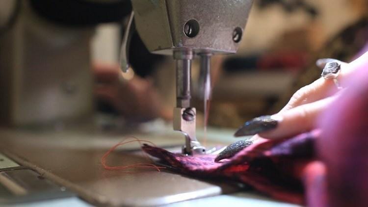 This is a close up image of Lindsey the company owner working on her industrial sewing machine at the Violet Flamingo studio.