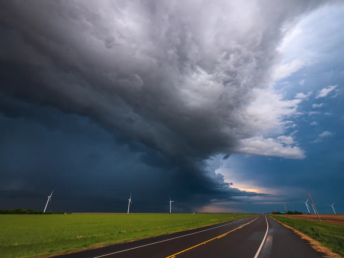 The formation of a large tornado over an empty road.