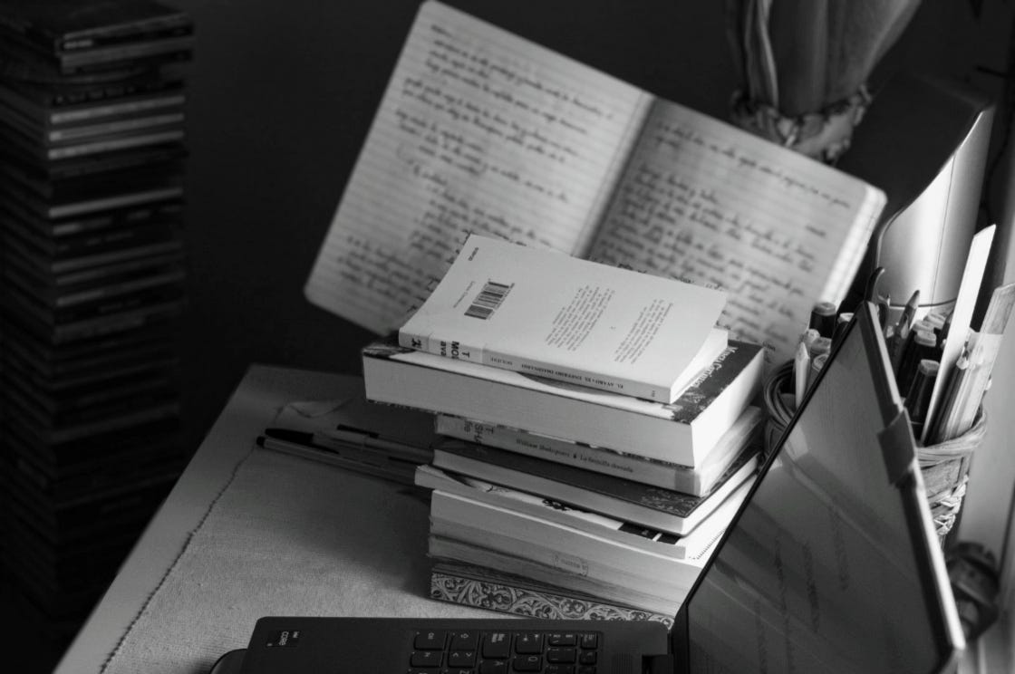A stack of books and a handwritten journal on the table. Photo taken by Diana Dolea
