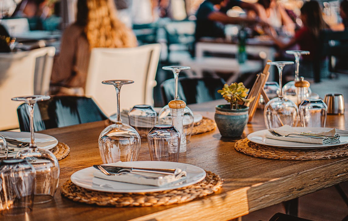 Picture of a wooden table with fine cutlery and plates representing fine dining