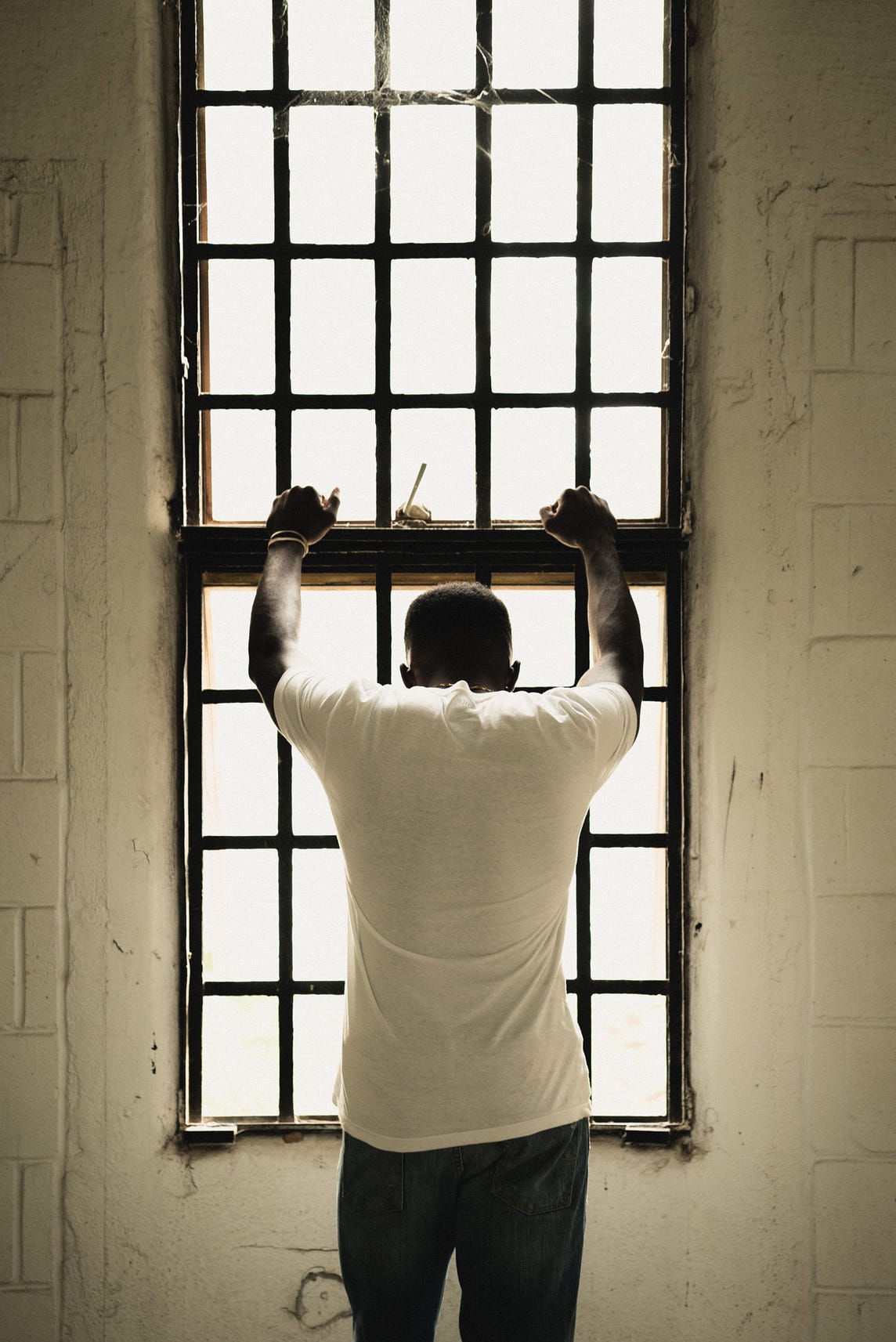 A Black man looking down through a prison window.