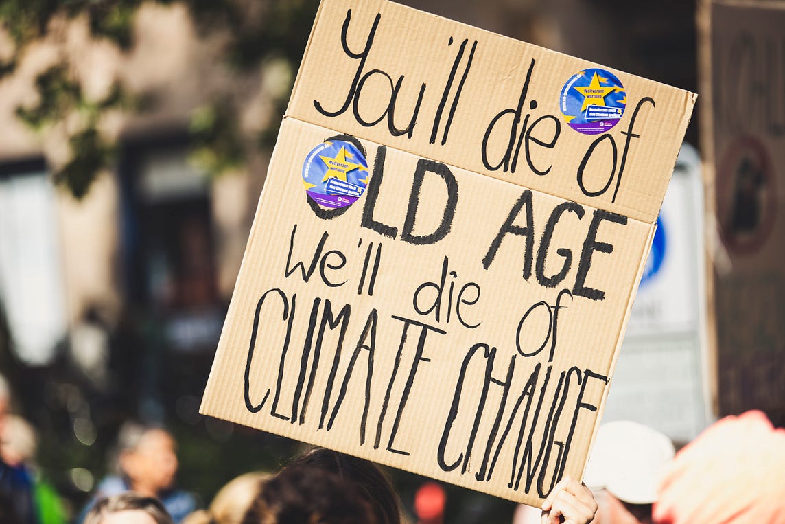 Photo of a climate banner saying ‘You’ll die of old age, we’ll die of climate change’