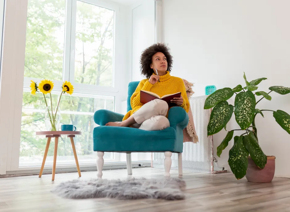 Woman curled up in a chair, thinking, with a pen and notebook.