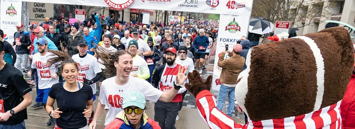 Runners high fiving a badger mascot