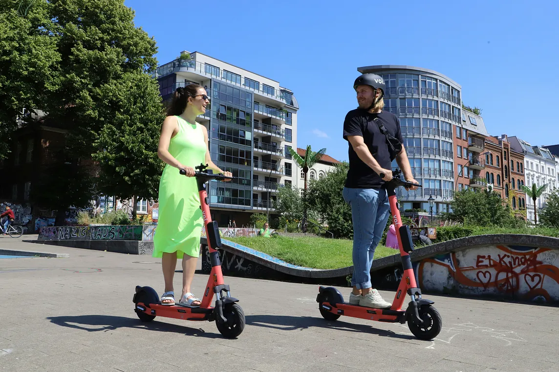 Two riders on e-scooters in an urban setting
