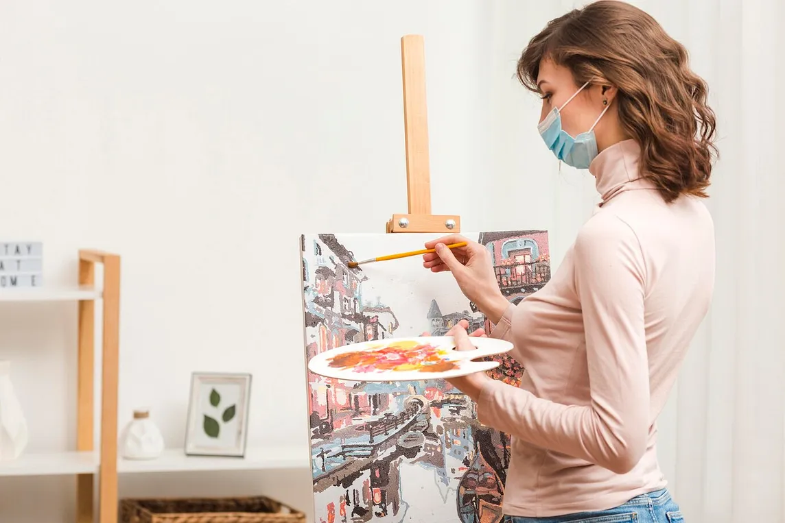 a woman holding a paintbrush in front of a canvas