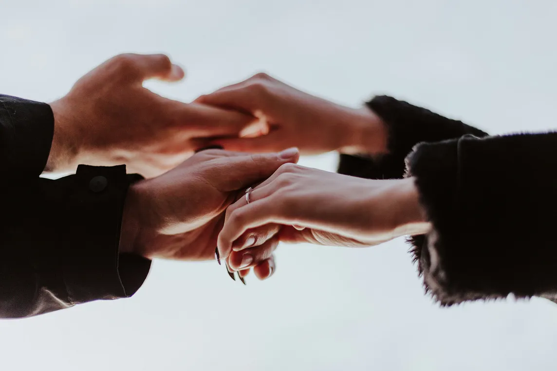 The hands of two people interlocked