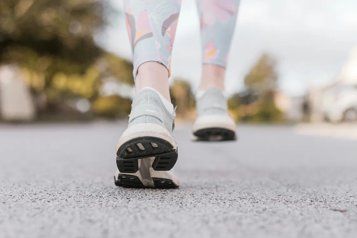 woman’s feet walking in athletic shoes on road