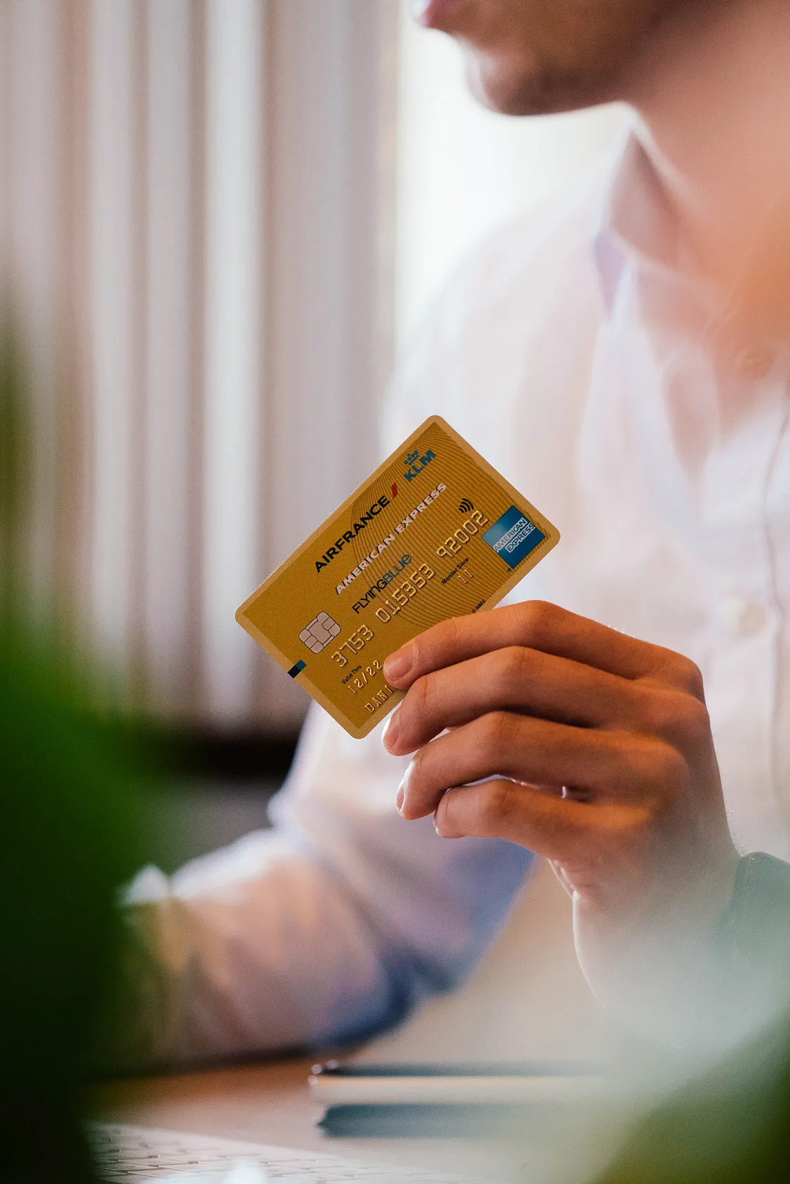 Someone holding an American Express credit card in their fingers.