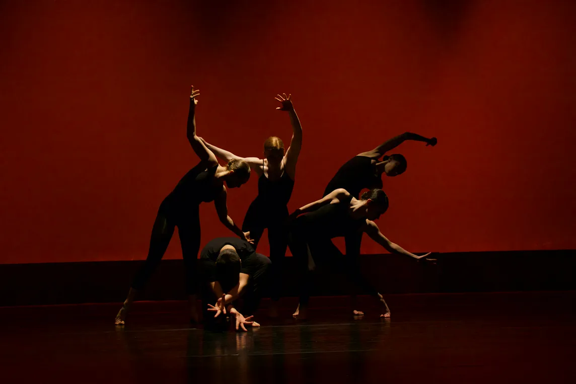 Five muscular actors on a stage, posing dramatically in shadows. Limited light invigorates their poses.