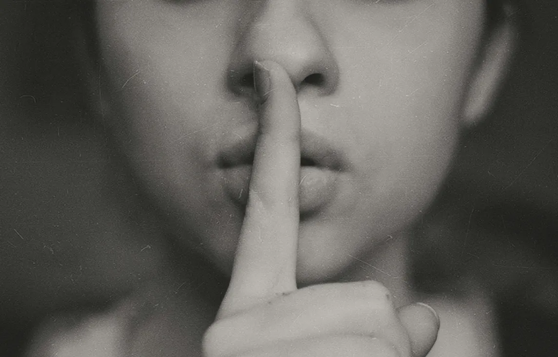 A lady with her pointer finger up to her lips as to be quiet and descreet.