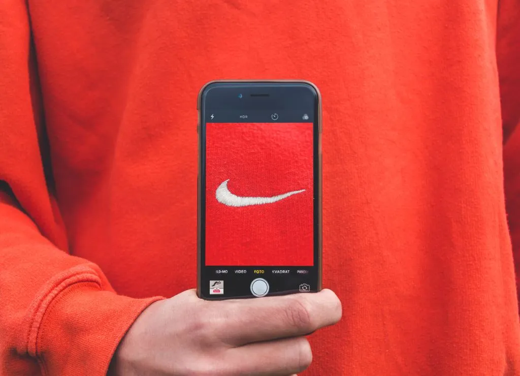 What is a trademark? Person holding iPhone taking picture of Nike label. Nike is a trademarked symbol.