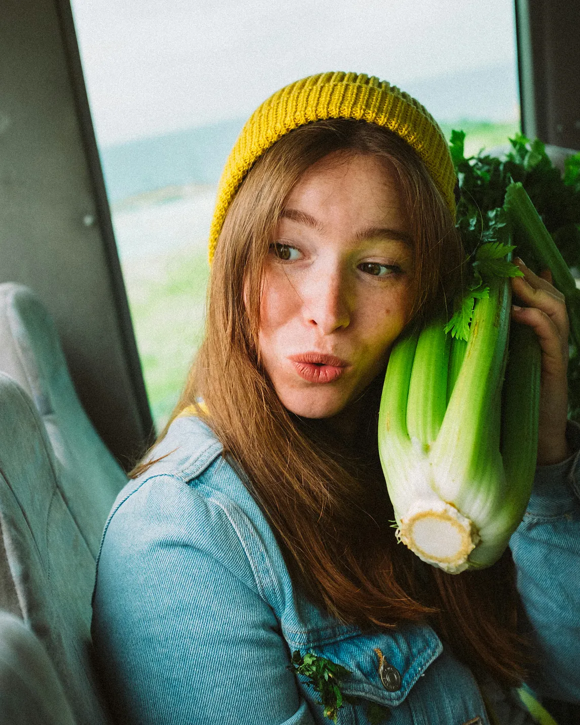 Woman holding a bunch of celery to her cheek