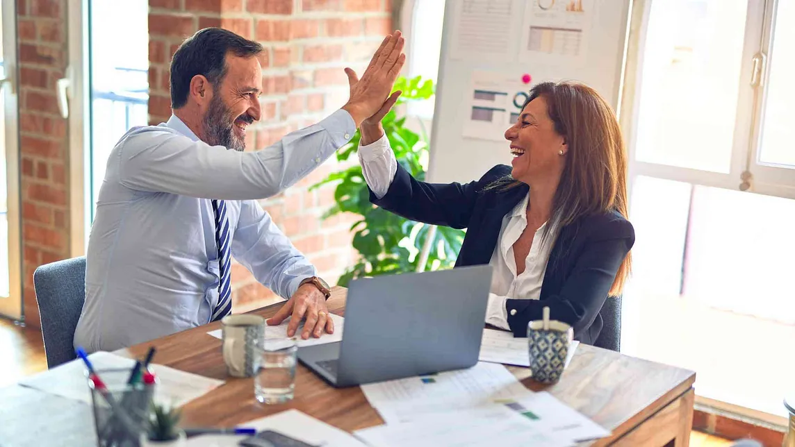 Two co-workers high fives.