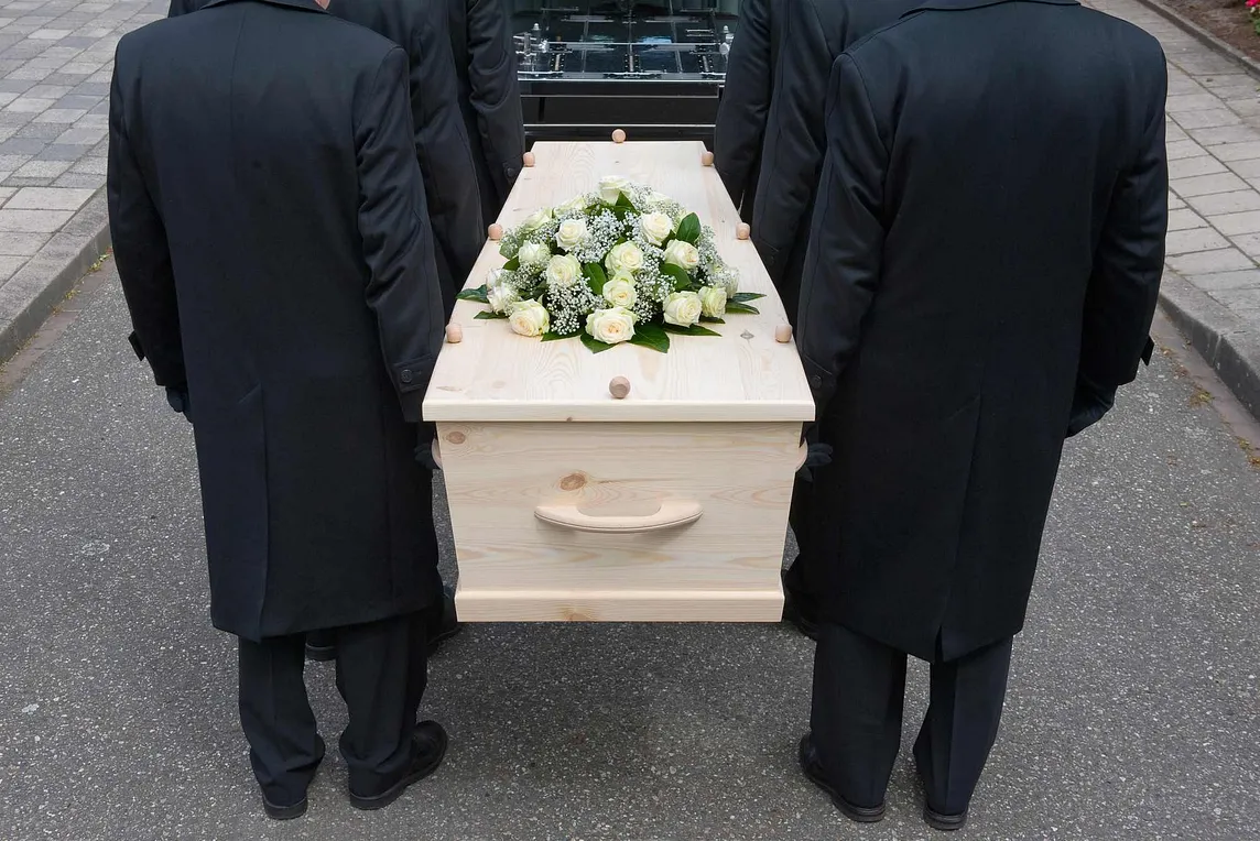 Bearers carrying a wooden coffin.