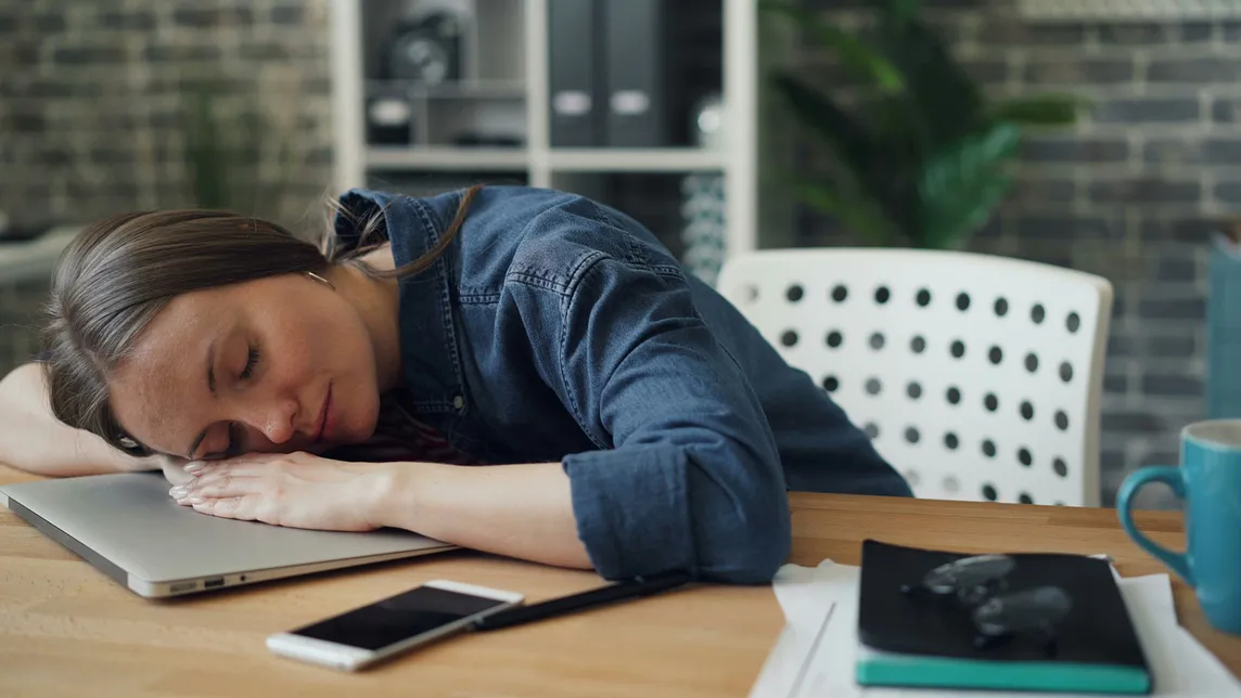 A young lady sleeping on her laptop.