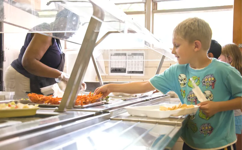 A student makes their way through a lunch line adding food to their tray. Image courtesy of the Public Health Image Library, Centers for Disease Control and Prevention.