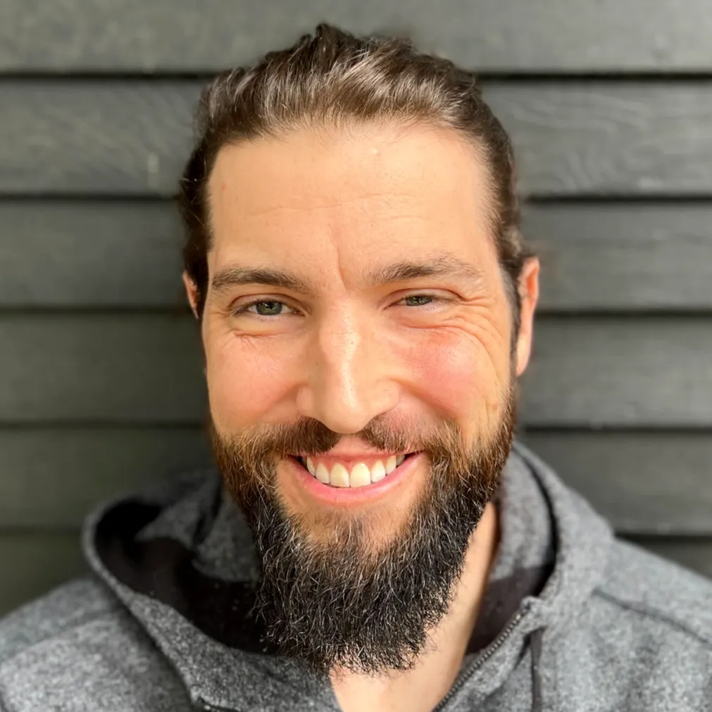 A photograph of Patrick Beukema, a man with brown hair and a brown beard wearing a grey hoodie.