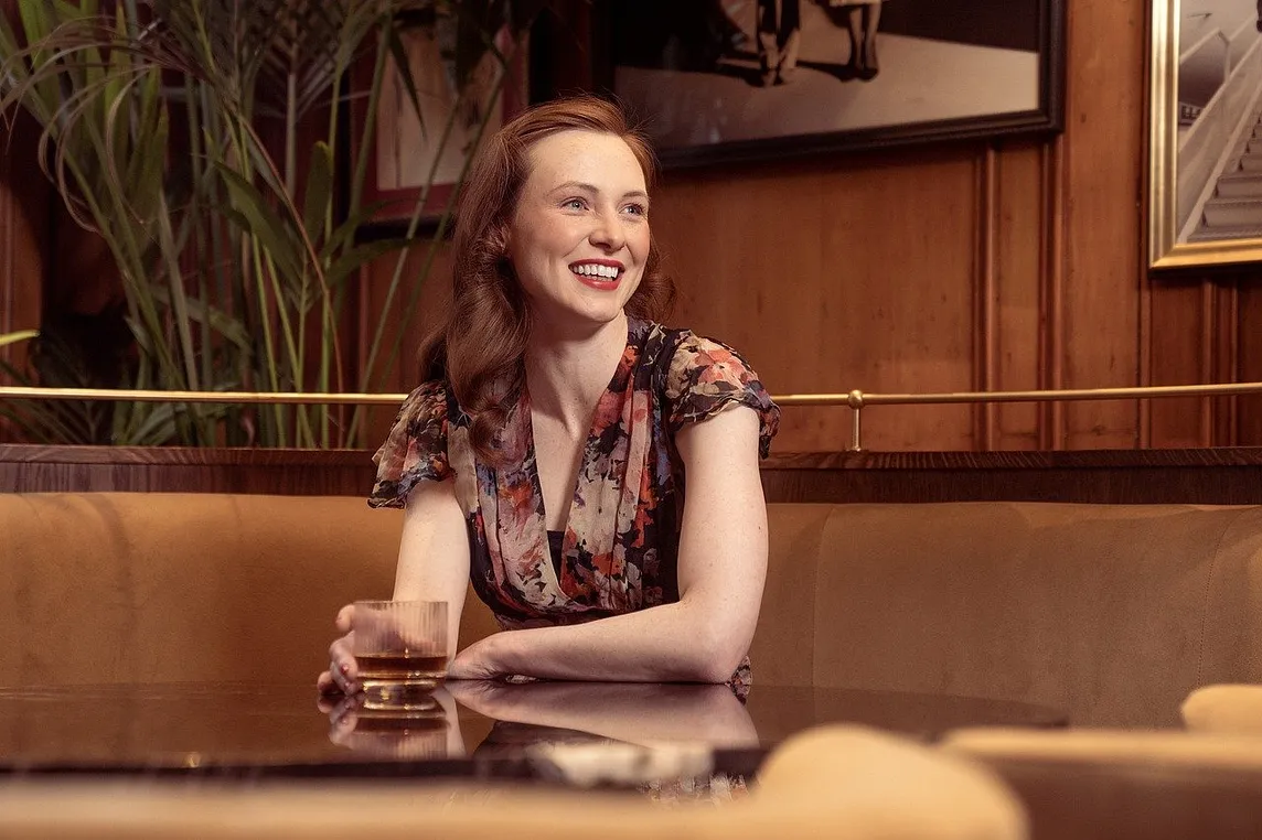 a woman smiling and holding a drink