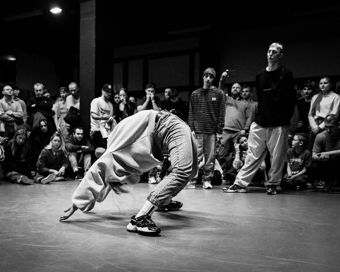 Black and white image of a battle dancer doing an extreme arch pose with their arms extended out above them.