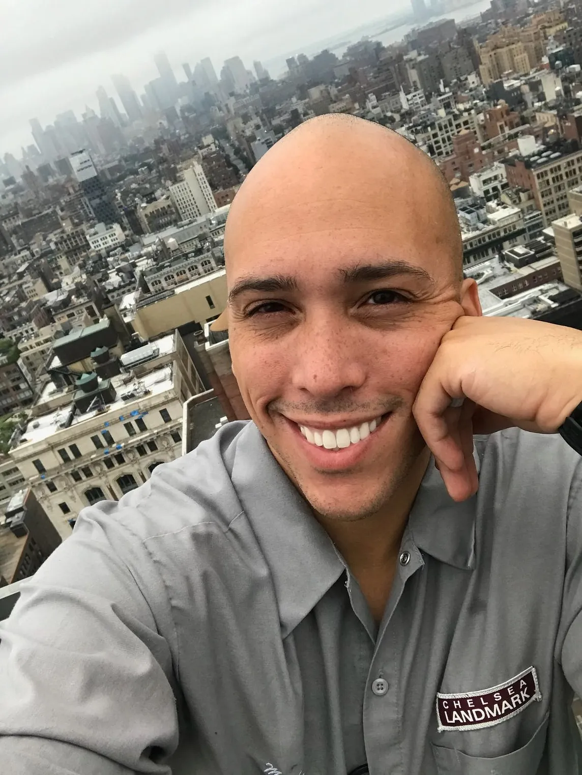 dark-eyed young man with brilliant smile, NY in the background