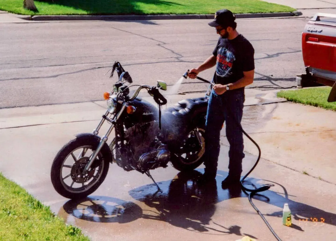 A photo from June 14, 1993, of the author cleaning his motorcycle in a driveway 1000 miles from home.