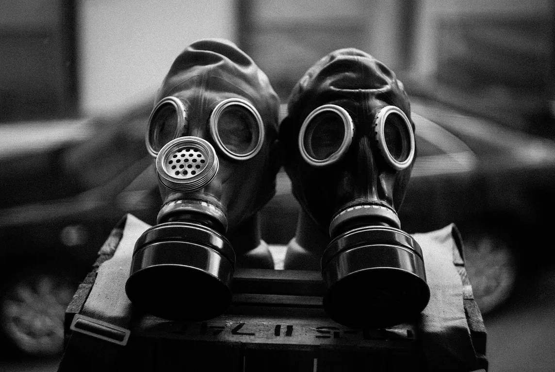 Two old gas masks sitting side by side. Photo is in black and white.