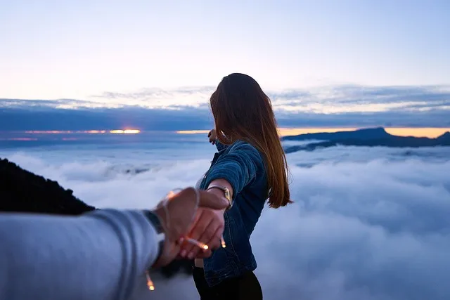 woman peering across an abyss while holding man’s hand.