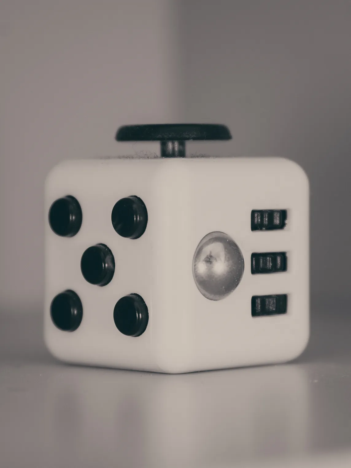 The background is blurry, and there is a black and white fidget cube in the foreground.