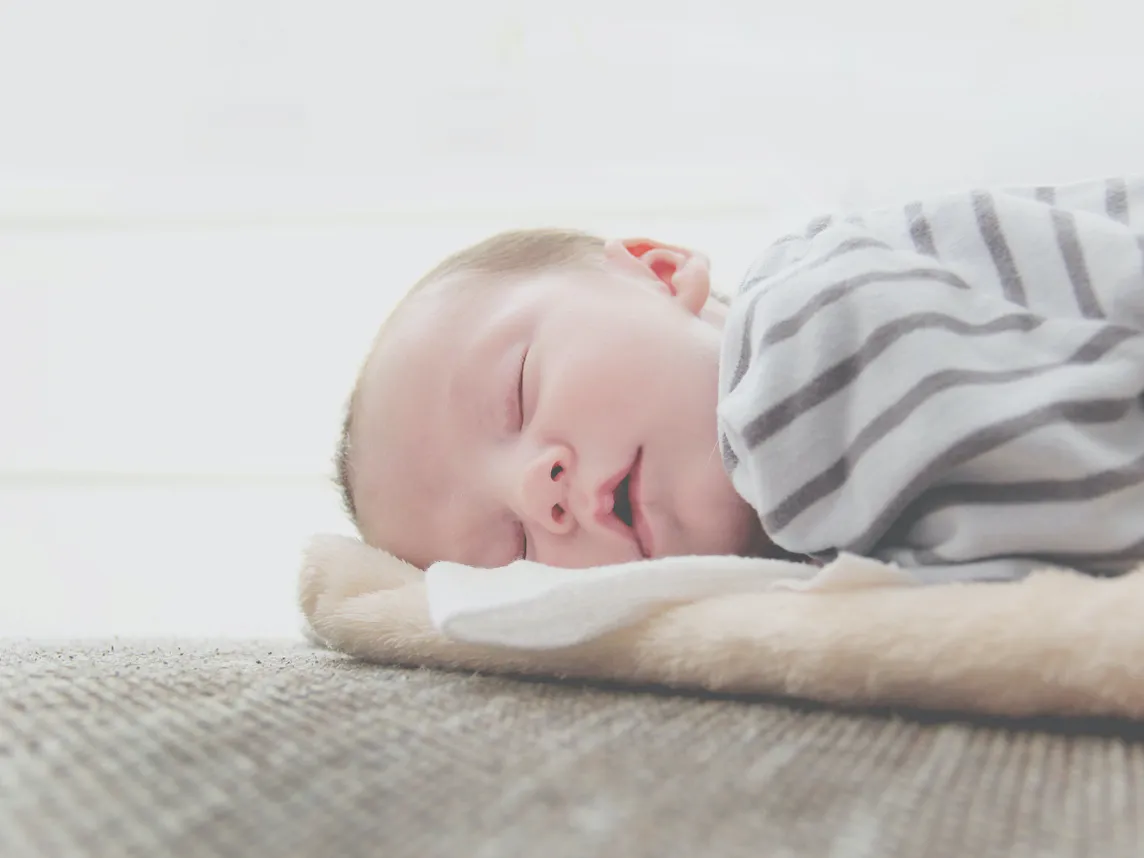 baby sleeping on blanket