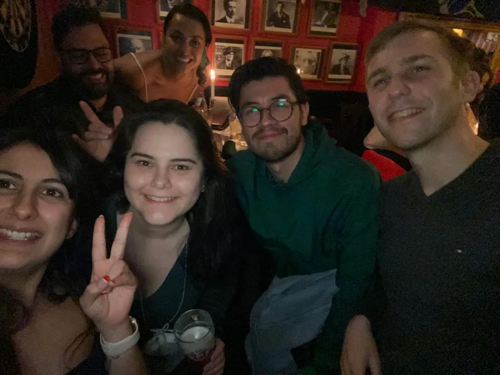 Six people pose together at a bar.