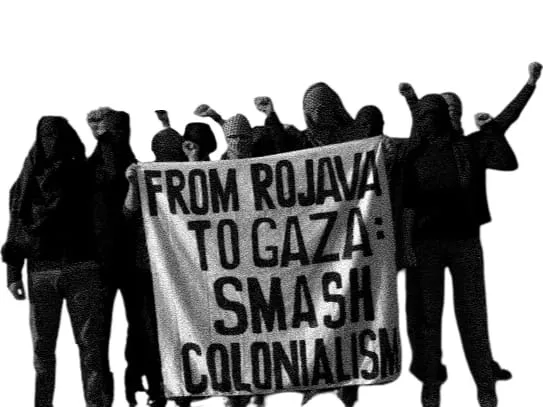 A protest sign reading “FROM ROJAVA TO GAZA: SMASH COLONIALISM”