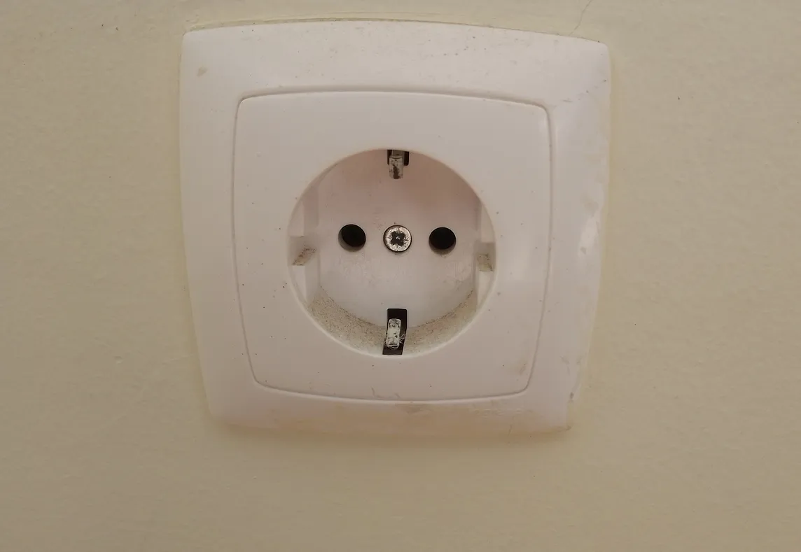 Very unexciting picture of a white type F wall outlet against a beigey/yellow wall. I probably should have dusted.