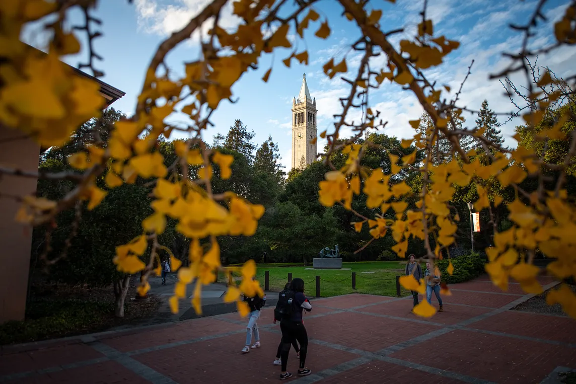 Students walking across campus with the Campanile in the background.