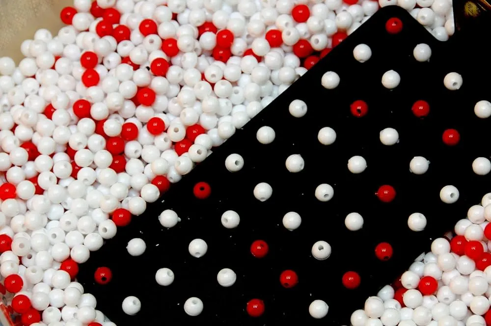 A black paddle in a pool of red and white beads is the setup to Deming’s famous Red Bead Experiment