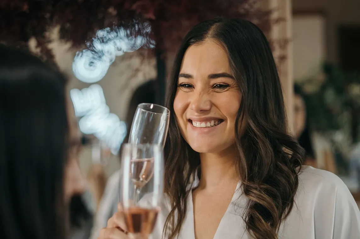 A woman smiling and holding a glass of champagne.