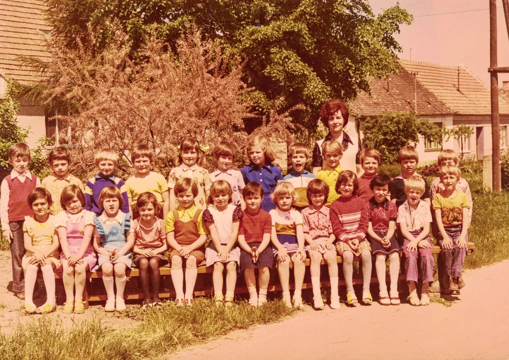 A teacher and her second grader students pose for a photo outside in front of the school.