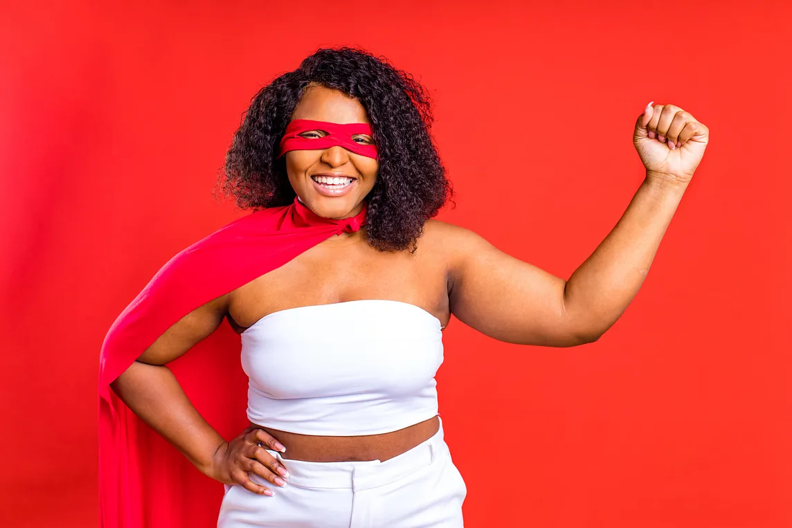 latin hispanic woman in red eye mask and long superhero cloak in studio background