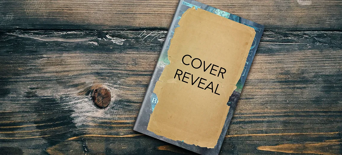 A book sitting on a wooden table. The cover of the book is covered with a piece of brown paper featuring the words “Cover Reveal.” The edges of the book cover can be seen around the edges of the paper, and the cover color is blue-green.