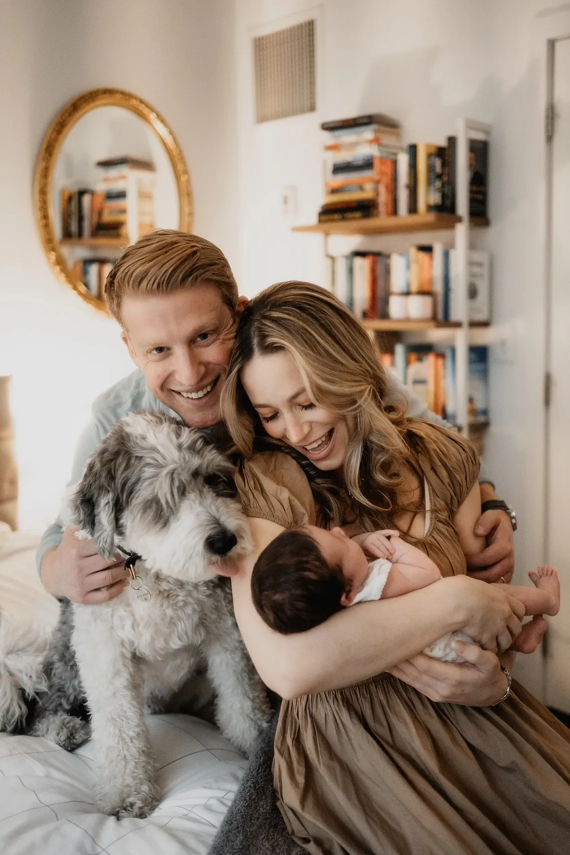 A smiling family with a father, mother, baby, and dog