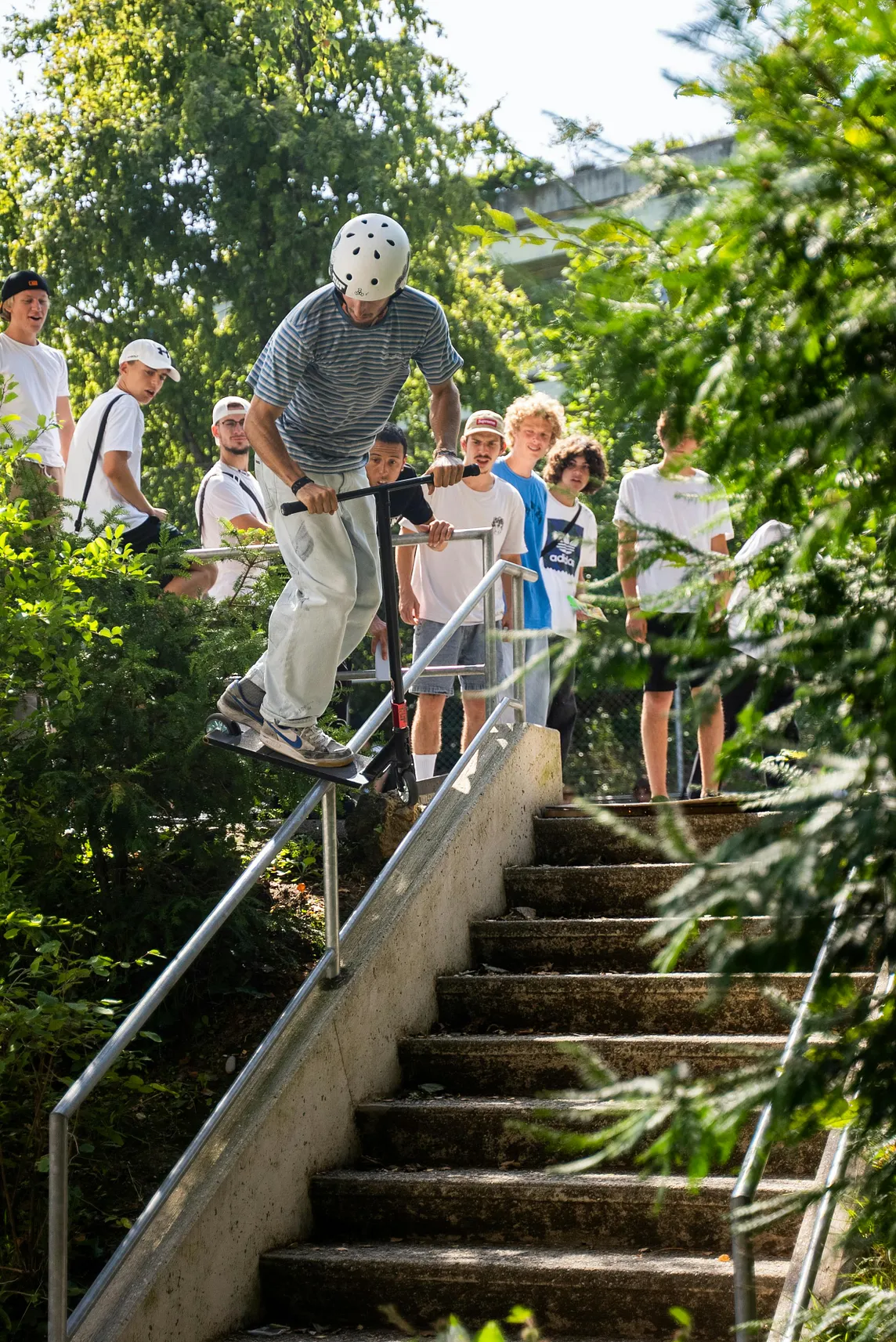 A Man Grinding a Scooter Trolley on a Handrail