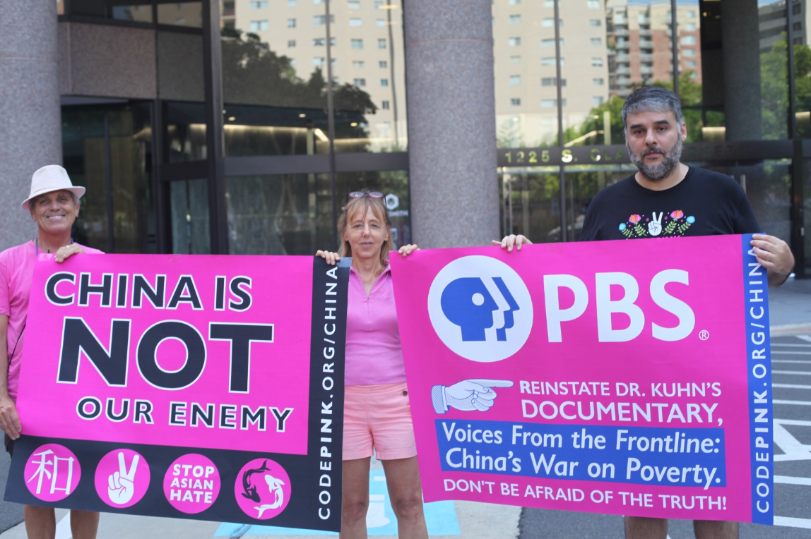 CODEPINK’s Tighe Barry, Medea Benjamin, and Leonardo Flores outside PBS HQ in Arlington, VA.
